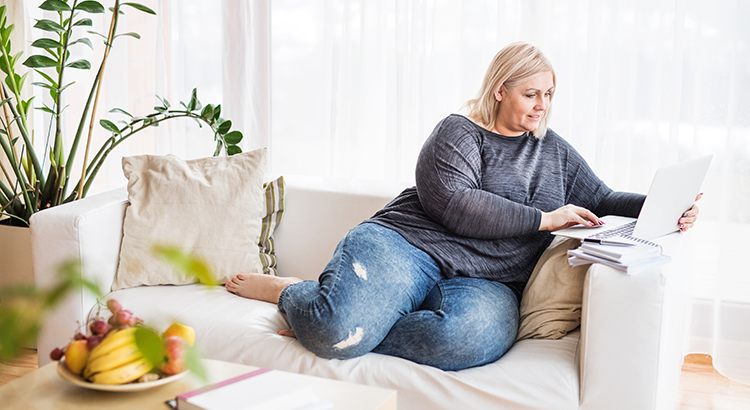 An attractive overweight woman at home, using laptop.