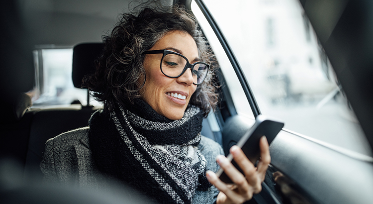 Mature businesswoman using phone while traveling by a taxi