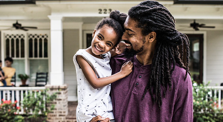 Portrait of father and daughter in front of home